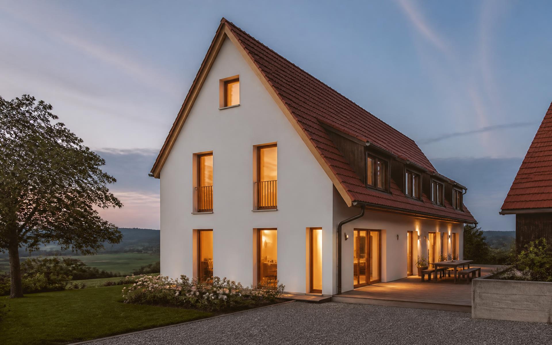 Wohnhaus mit Satteldach und Holzfenstern in der Abenddämmerung in Oberschwaben